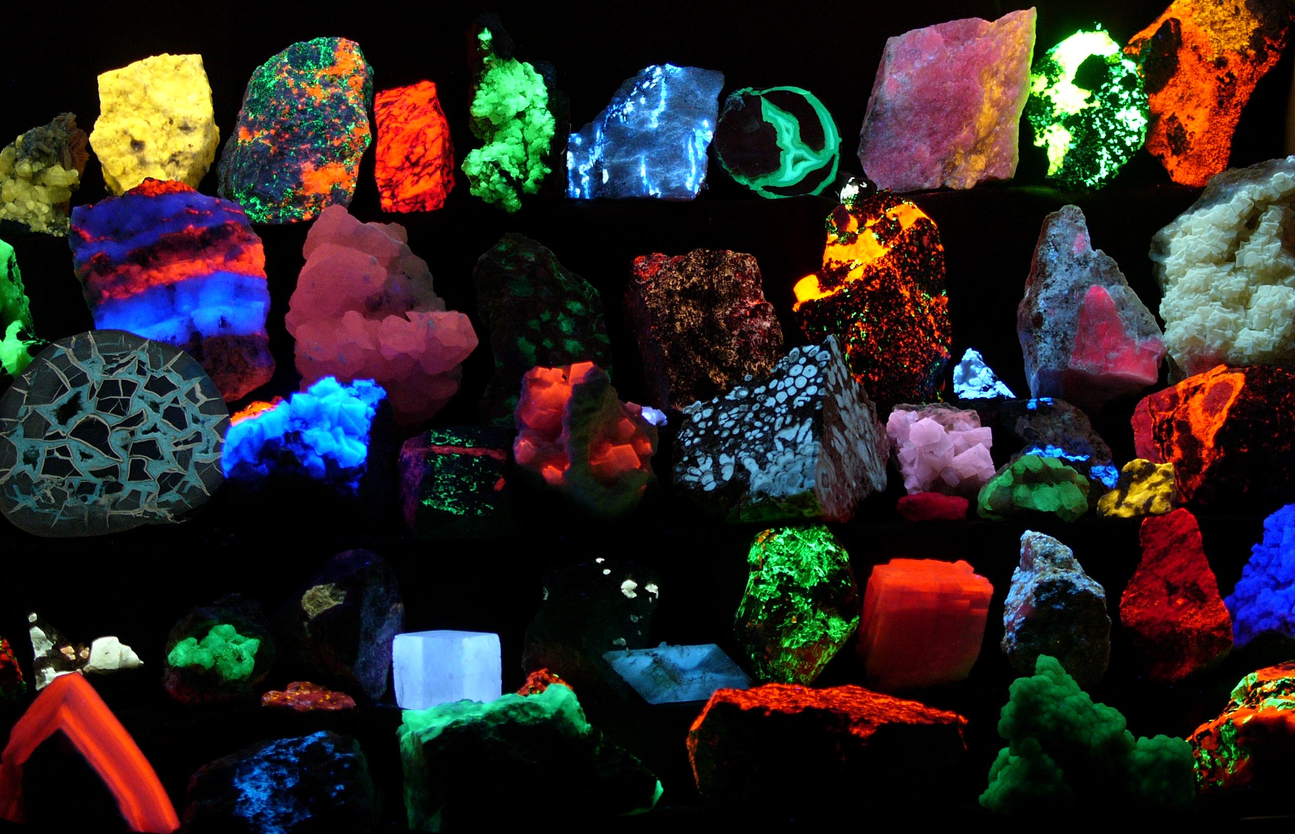 Mineral specimens glowing green and orange under shortwave ultraviolet light