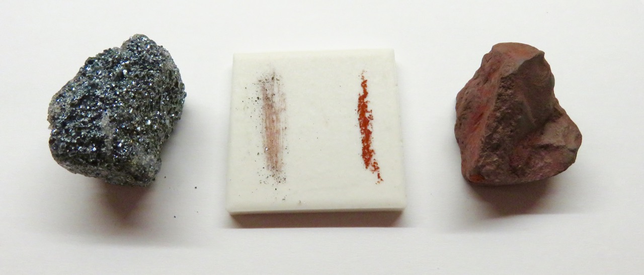 Dark hematite mineral dragged across a white porcelain streak plate, leaving a reddish-brown streak