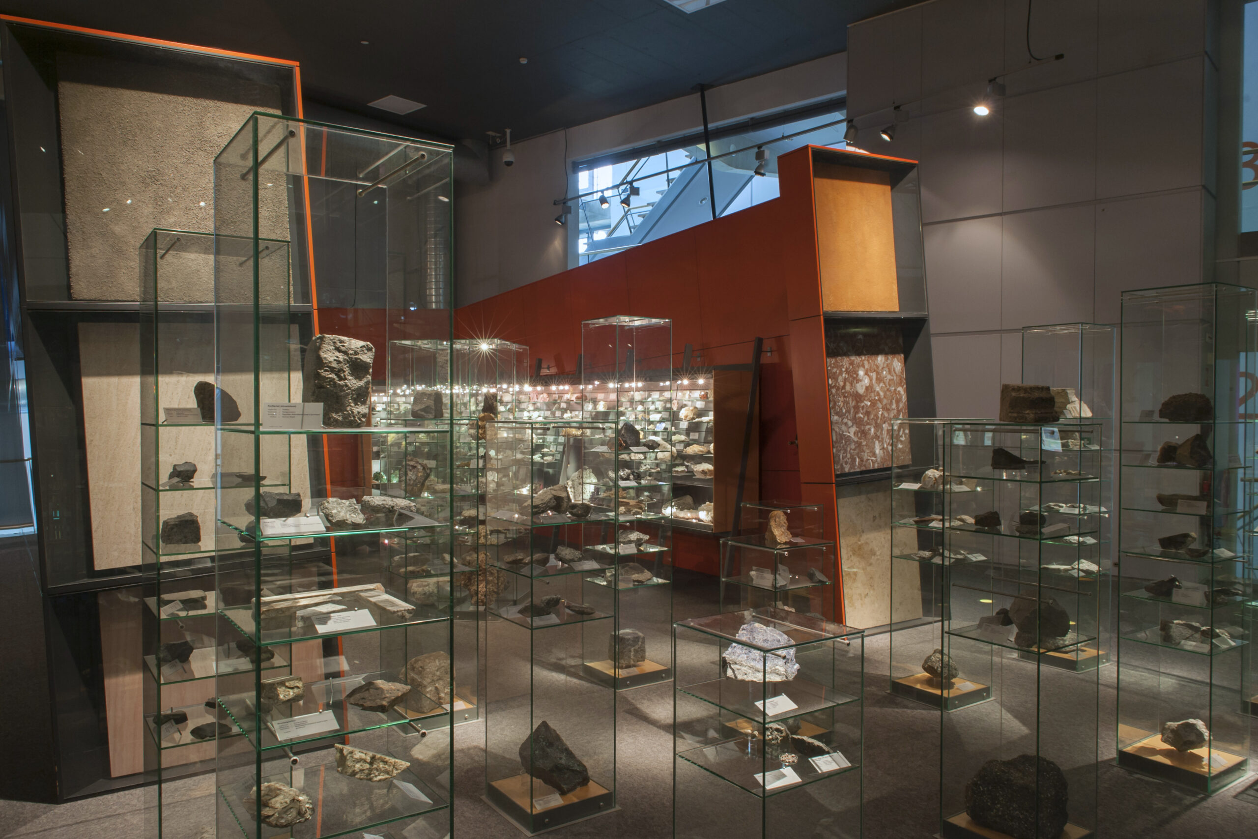 Museum display of labelled mineral specimens arranged in lit cases
